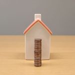 a miniature house and a stack of coins