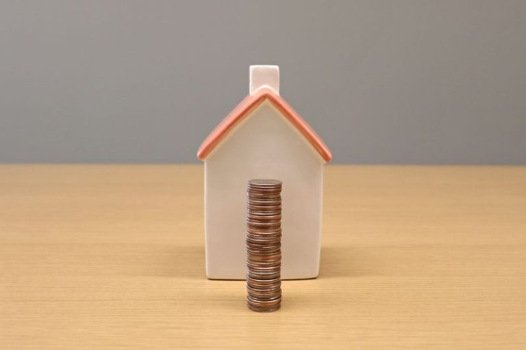 a miniature house and a stack of coins
