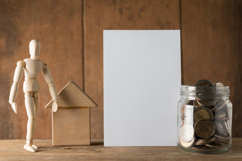 money in a jar and a miniature human toy with a small house